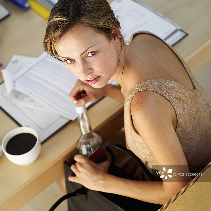年轻女子打开一瓶伏特加的高角度视图图片素材