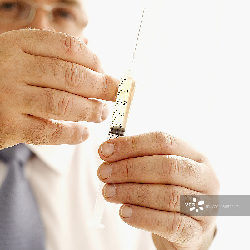 男医生轻弹注射器特写镜头图片素材