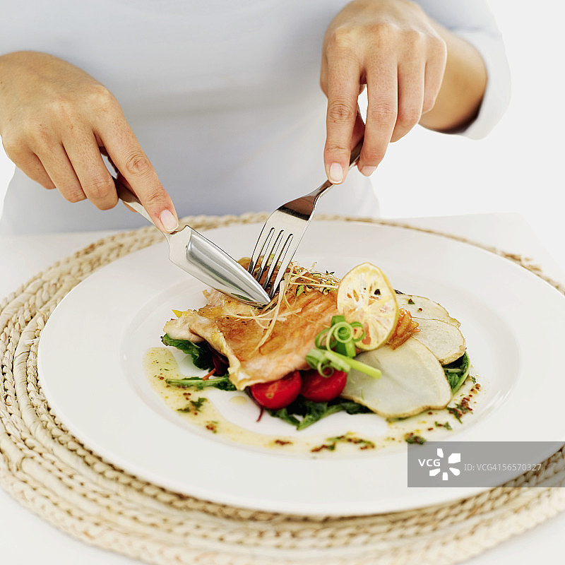 人物用刀叉吃烤鲑鱼图片素材