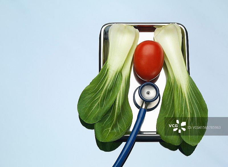 医疗托盘上的听诊器、番茄和小白菜，象征健康肺和心脏图片素材