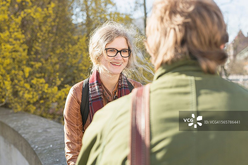 与坐在墙上的男性朋友在一起的微笑少女图片素材
