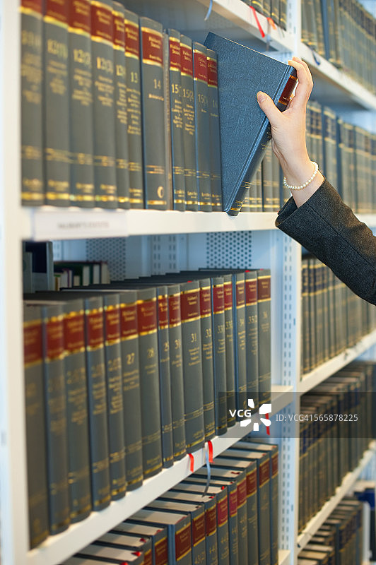 白人女商人从法律图书馆的书架上取书图片素材