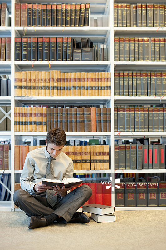 在法律图书馆地板上阅读的白人男商人图片素材