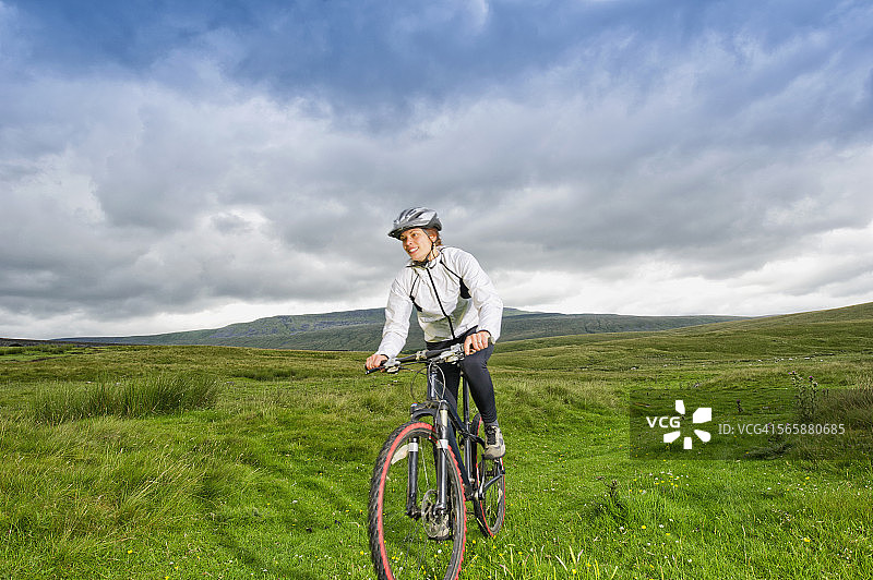 白人女性在乡村田野骑山地自行车图片素材