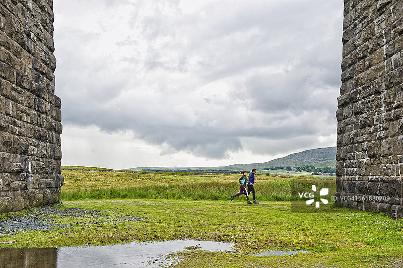 白人情侣在乡村田野的石墙附近慢跑图片素材