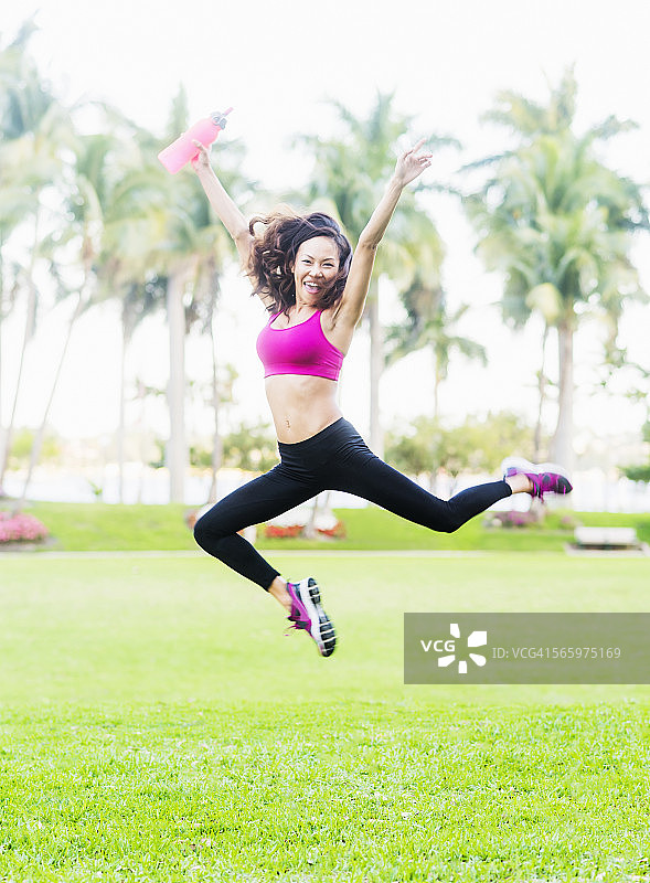 在公园里高兴地跳跃的中国女人图片素材