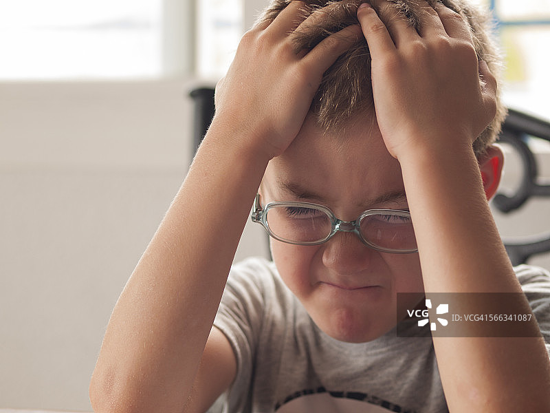 沮丧的男孩坐在桌旁图片素材
