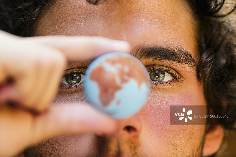 手持微型地球仪的西班牙裔男子特写图片素材