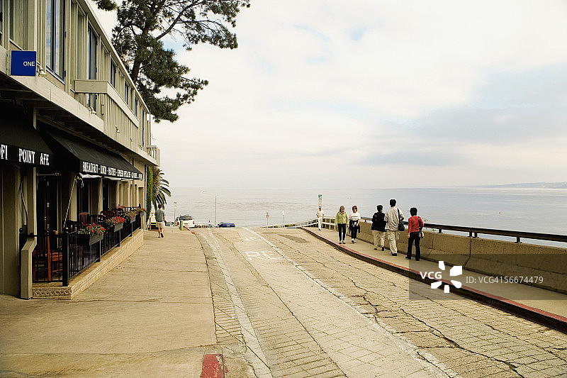 在美国加利福尼亚州圣地亚哥拉霍亚海湾的咖啡馆外行走的人群图片素材