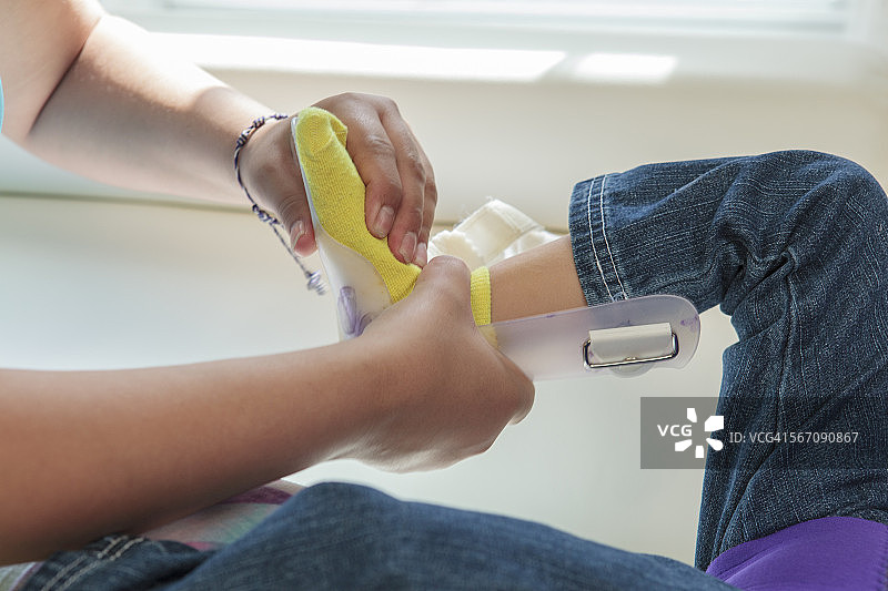 妈妈给患有脑瘫的小女儿戴腿部支架图片素材