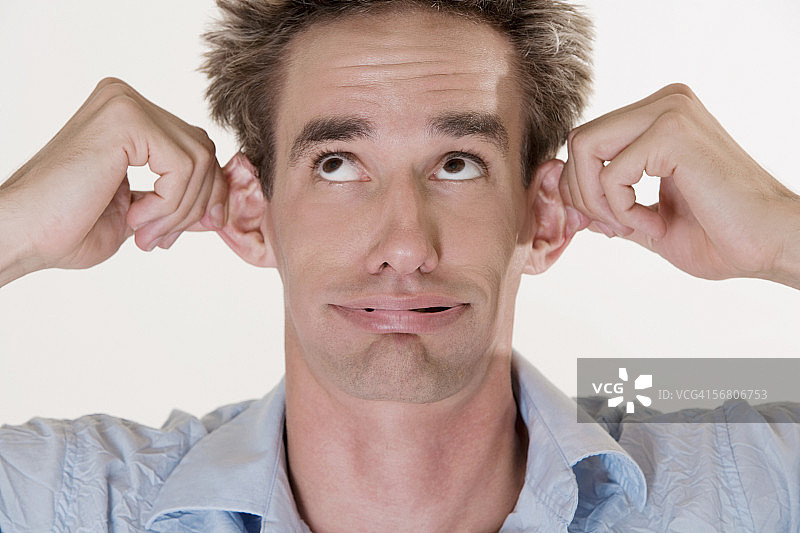 捂住耳朵的年轻男子特写图片素材