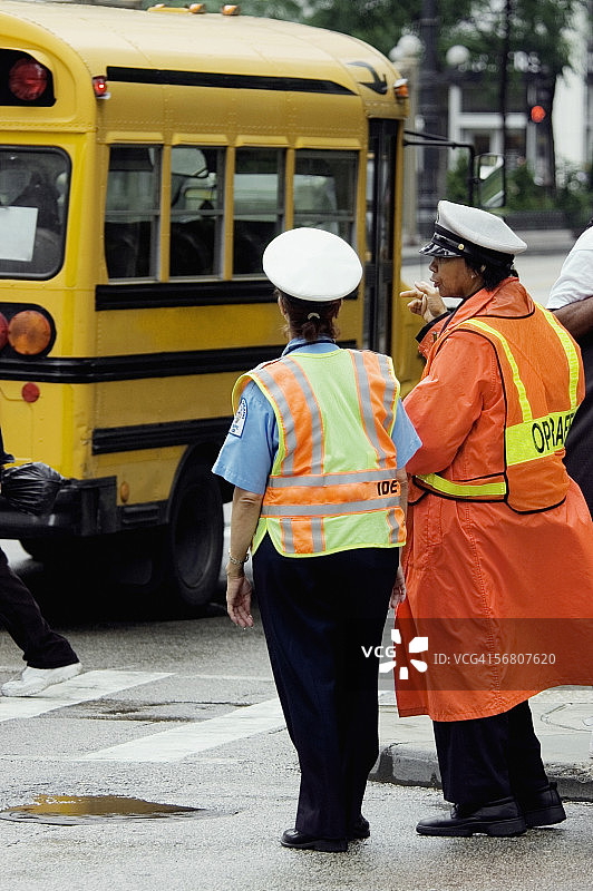 美国伊利诺伊州芝加哥，两位站在校车旁的护送员后视图图片素材