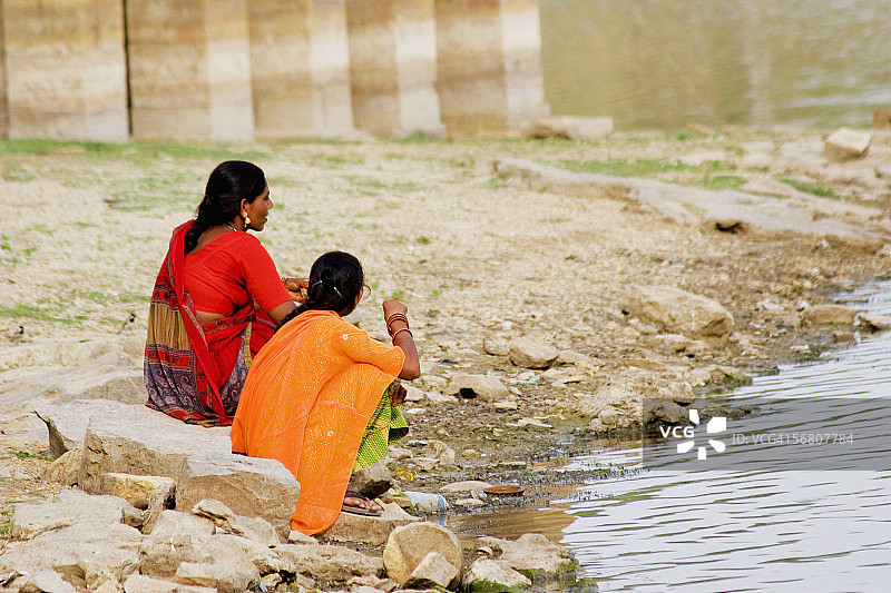 两位女士坐在印度拉贾斯坦邦斋沙默尔Gadi Sagar河岸边图片素材