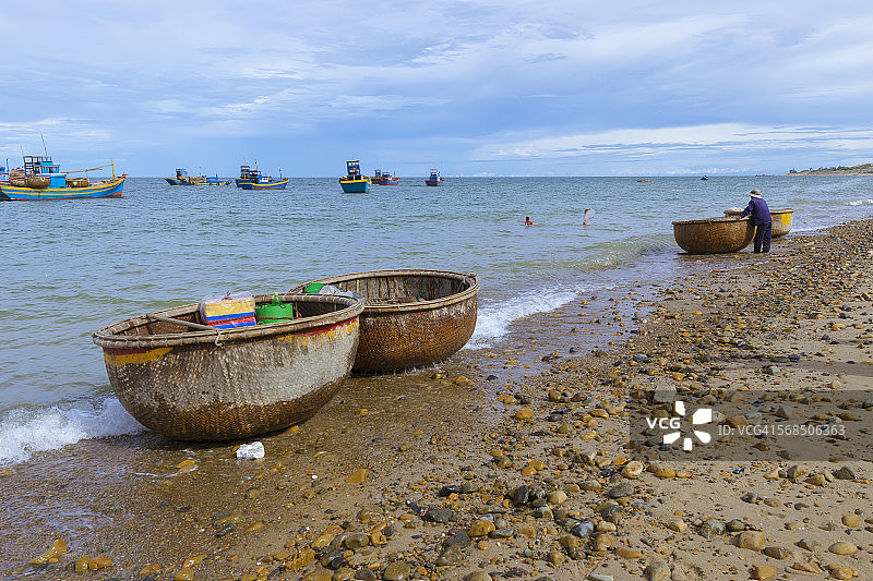 在海滩上作业的渔夫与小舟图片素材