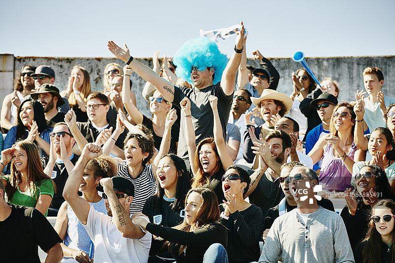 戴假发的男人在足球比赛中带领人群欢呼图片素材