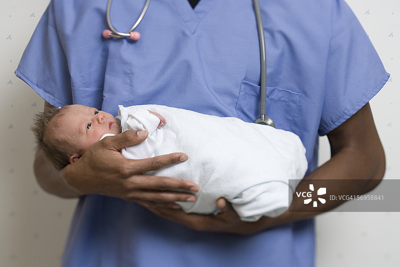 男医生抱着新生男婴的腰部视角图片素材
