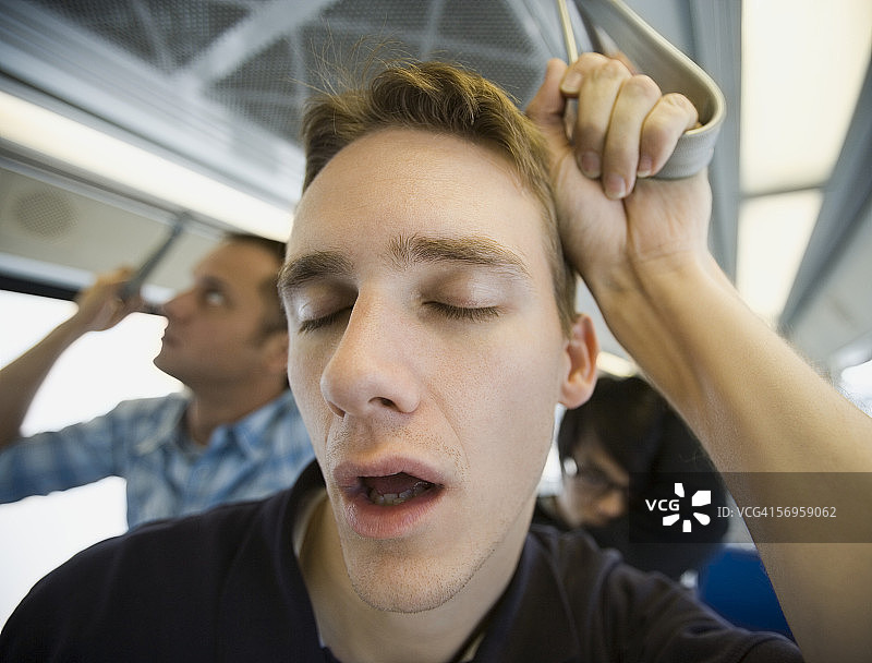 特写：年轻男子在通勤列车上睡觉图片素材