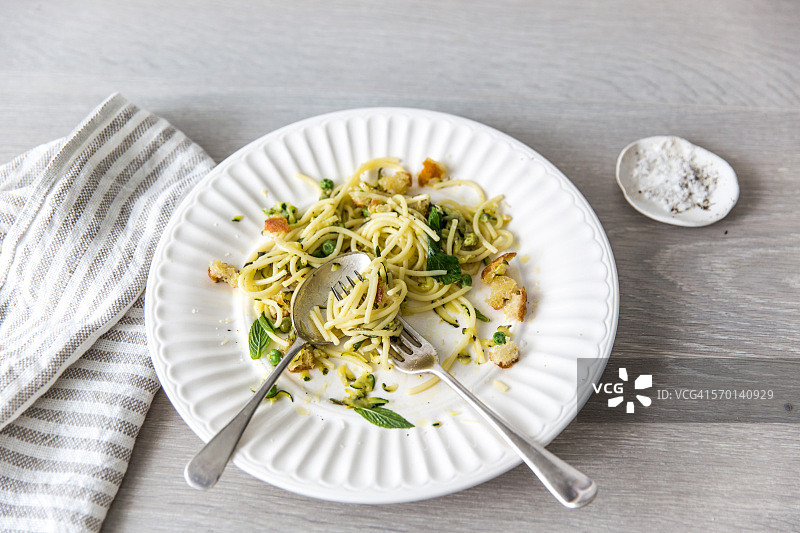 吃了一半的意面，配有豌豆、薄荷、柠檬、面包和帕尔马干酪图片素材