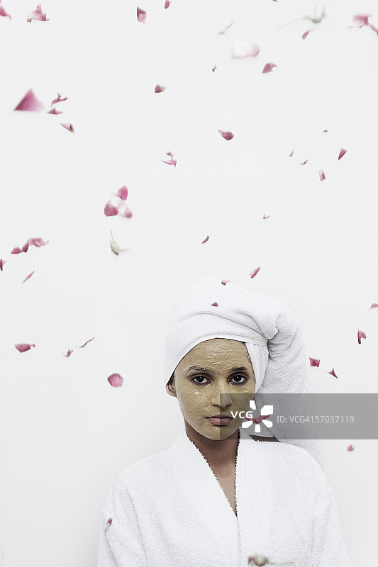 敷面膜、玫瑰花瓣飘落的年轻女子肖像图片素材