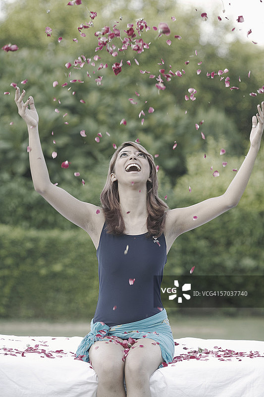 在空中抛洒玫瑰花瓣的年轻女人图片素材