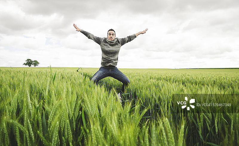 在麦田里跳跃的年轻男子图片素材