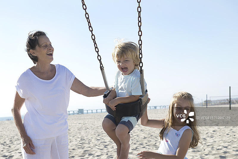 奶奶和女孩一起推着男孩荡秋千图片素材