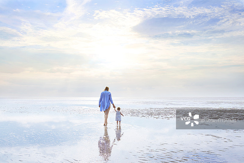母女在退潮的日落时分散步图片素材