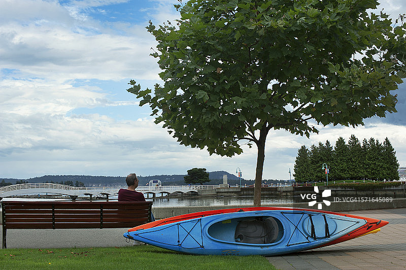 男子坐在加拿大纳奈莫的皮划艇旁图片素材
