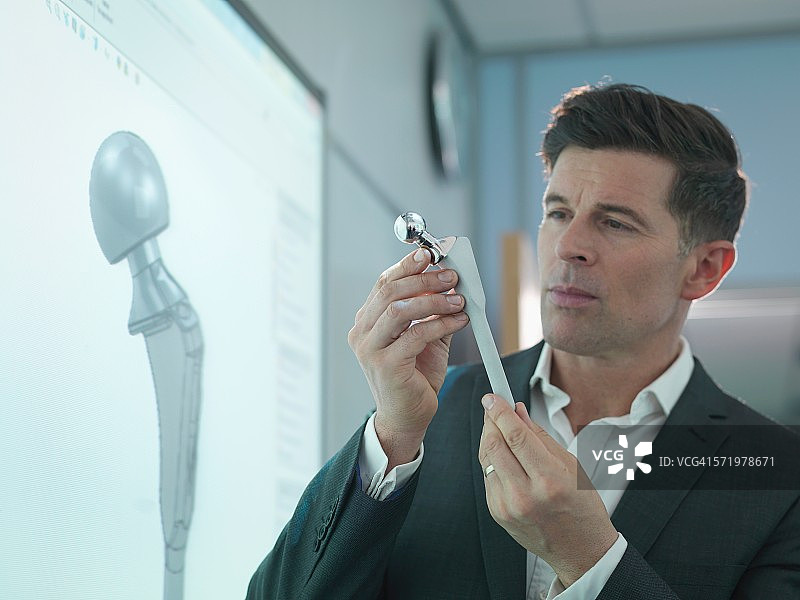 医疗产品设计师检查带有图形屏幕的髋关节模型图片素材