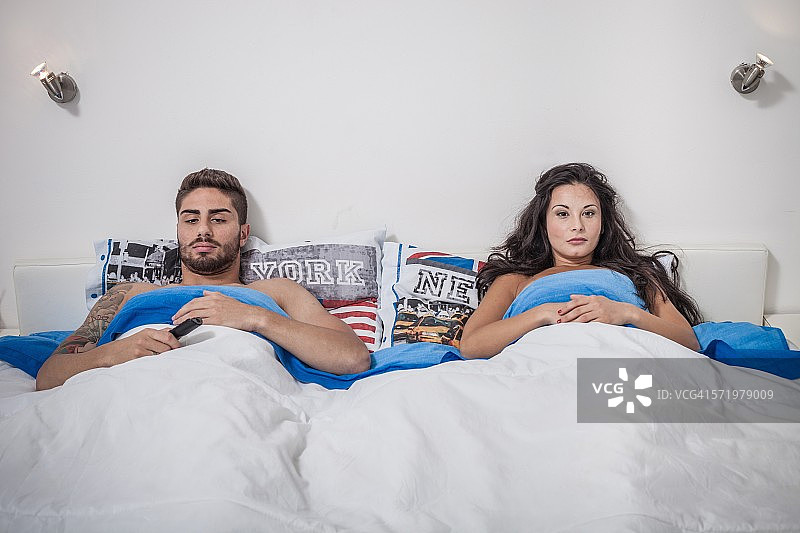 年轻夫妇躺在床上生闷气图片素材