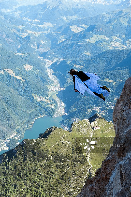 男性低空跳伞运动员在意大利多洛米蒂山谷进行翼装飞行图片素材