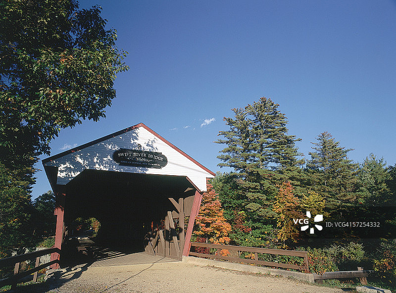 秋季，斯威夫特河大桥标志悬挂在通往廊桥的入口上方。斯威夫特河大桥，新罕布什尔州康威图片素材