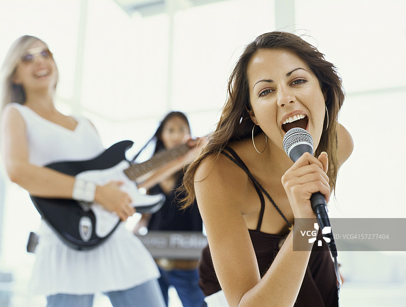 年轻女人唱歌，另有两位年轻女人演奏乐器的肖像图片素材