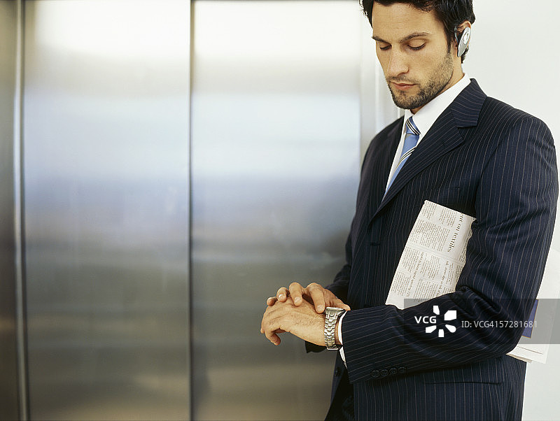 等待电梯的商人看手表的特写图片素材