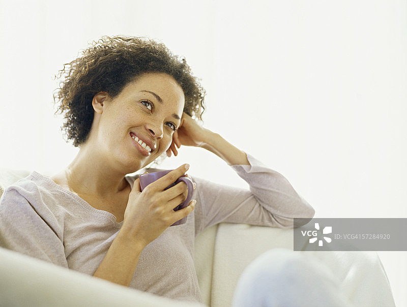 年轻女人手持茶杯坐着图片素材