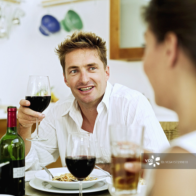 年轻夫妇在餐桌旁吃东西和喝葡萄酒图片素材