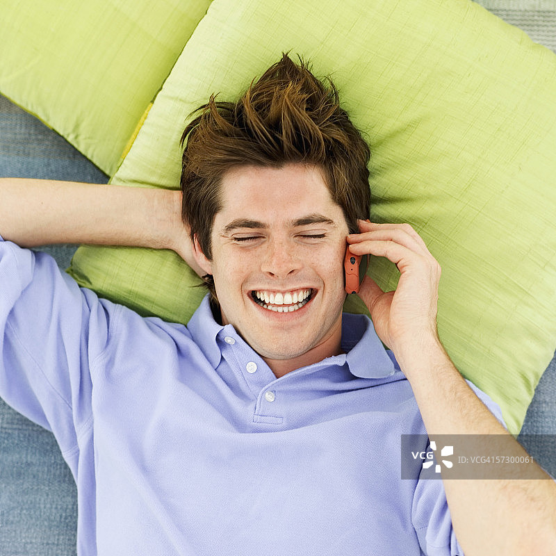 躺在床上使用手机的年轻男子高角度视图图片素材