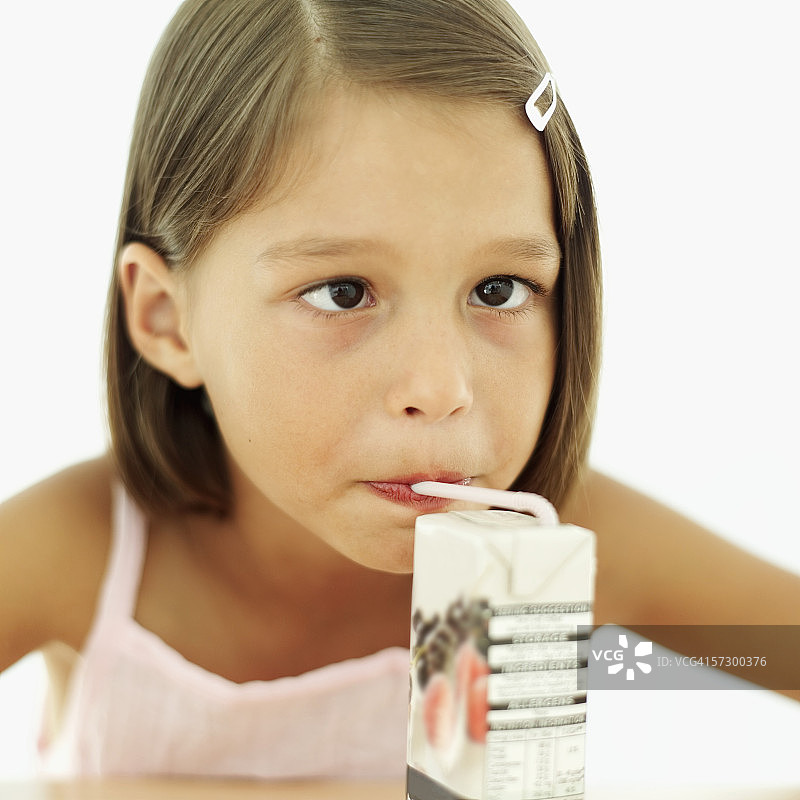 年轻女孩（8-9岁）用吸管喝果汁饮料图片素材