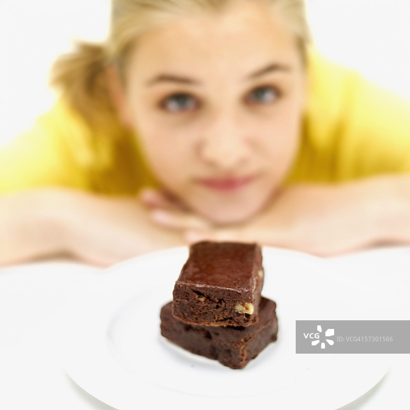 看着一盘巧克力布朗尼蛋糕的少女（15-17岁）（模糊）图片素材