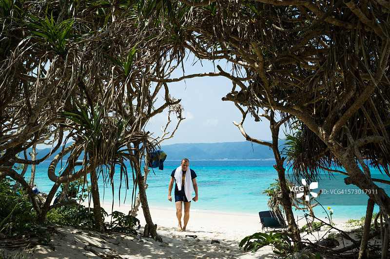 男人走在有露兜树的热带海滩上图片素材