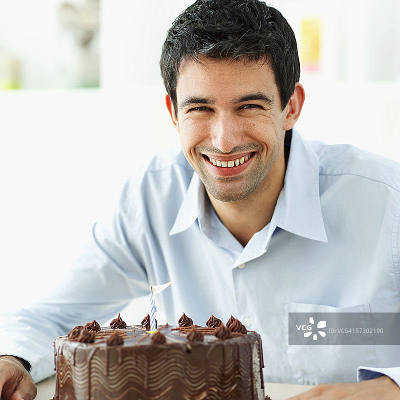 男子手捧巧克力生日蛋糕微笑的肖像图片素材