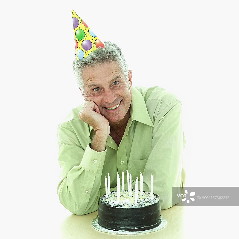 一位坐在生日蛋糕后的年长男士肖像图片素材