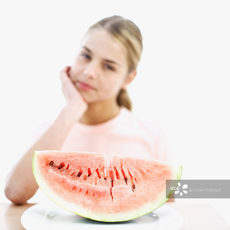 年轻女子凝视着盘子里的一片西瓜（模糊）图片素材