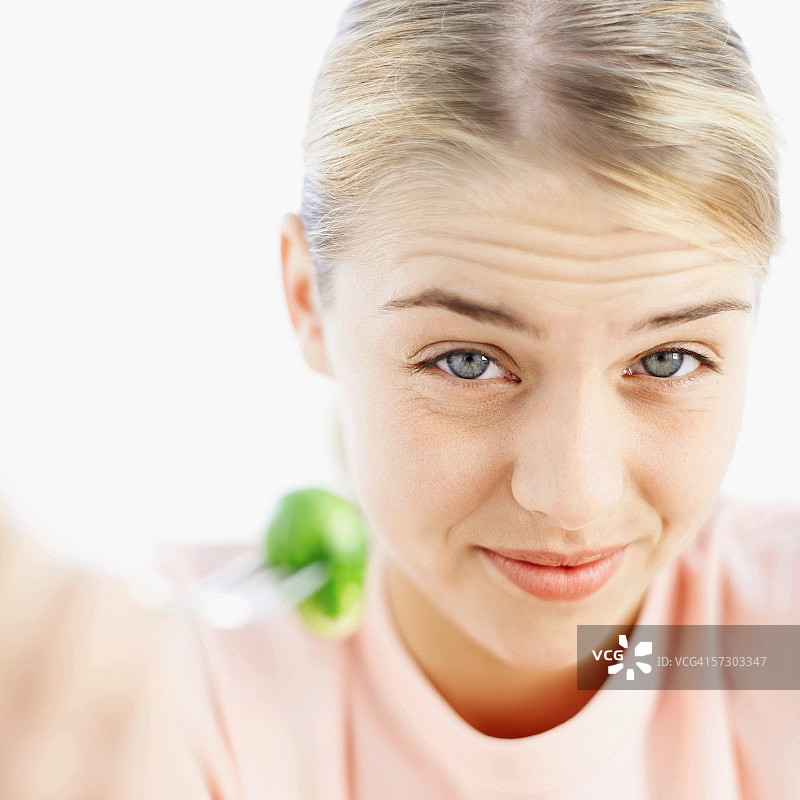年轻女人皱眉看着叉子上的球芽甘蓝特写图片素材