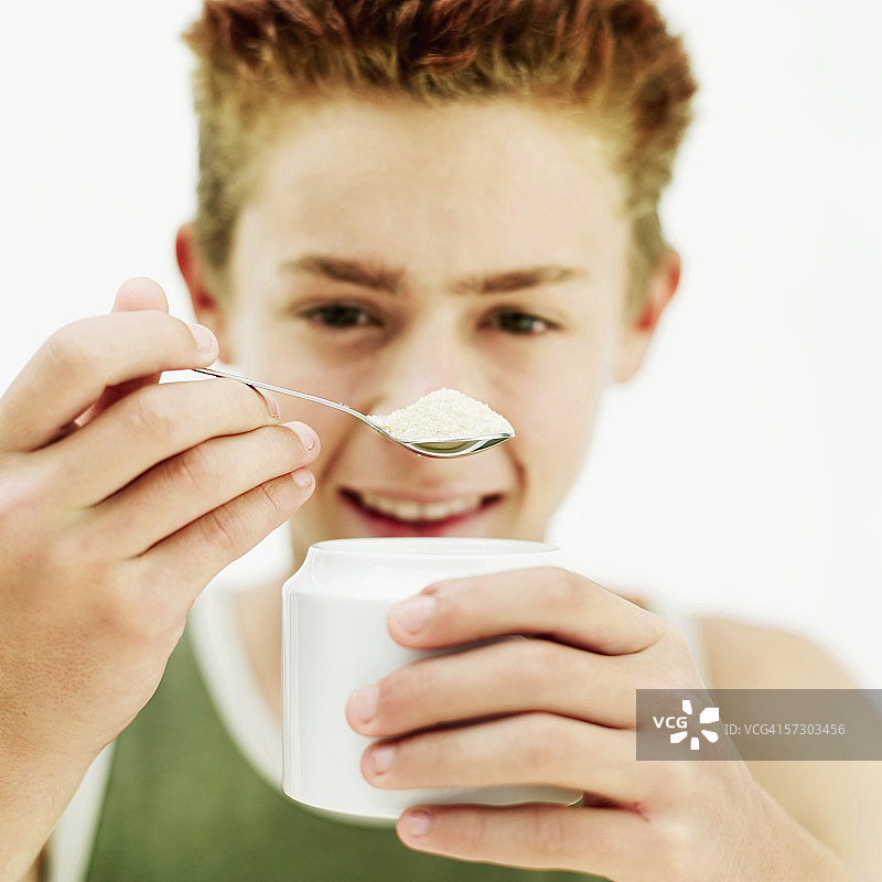 拿着一茶匙糖的青少年男孩（15-17岁）特写图片素材