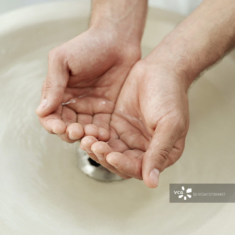 男人在水槽上方接水的俯视图图片素材