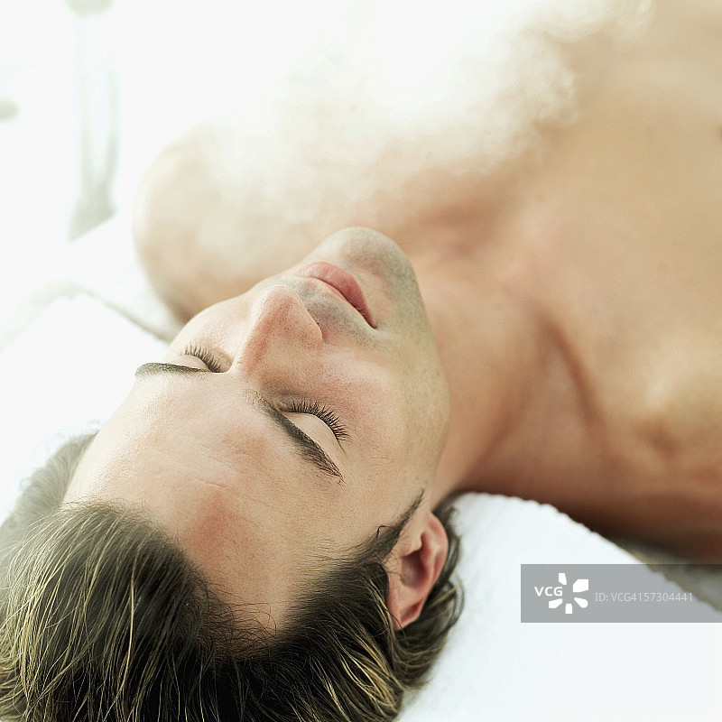 年轻男子在水疗中心躺下的俯视图图片素材