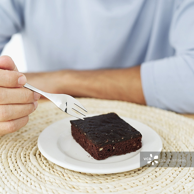 用叉子吃巧克力蛋糕的年轻人图片素材