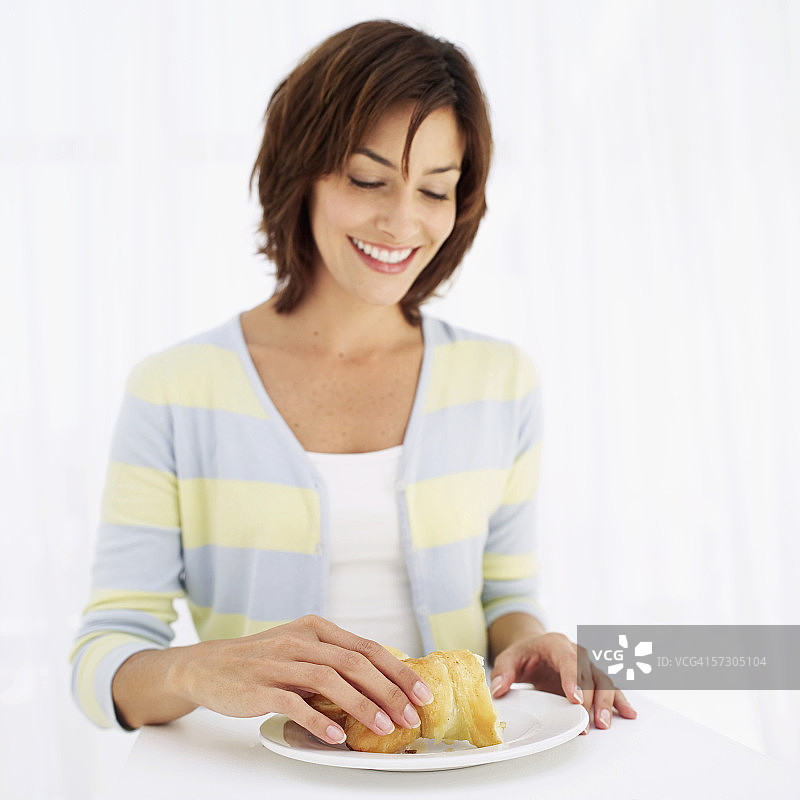 年轻女人手持盘子里的羊角面包图片素材