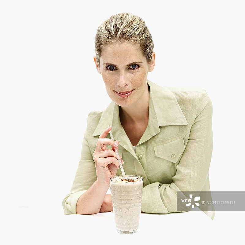 手拿奶昔玻璃杯和吸管的年轻女性肖像图片素材